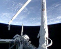 A video camera aboard space shuttle Discovery captured this view of the shuttle's payload bay and robotic arm as the vehicle soared above the Earth. 
