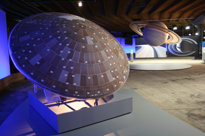 Sonden, Planetengloben und Plakate sind gekonnt in Beziehung gesetzt. Im Vordergrund Huygens' Hitzeschild, im Hintergrund der Saturn