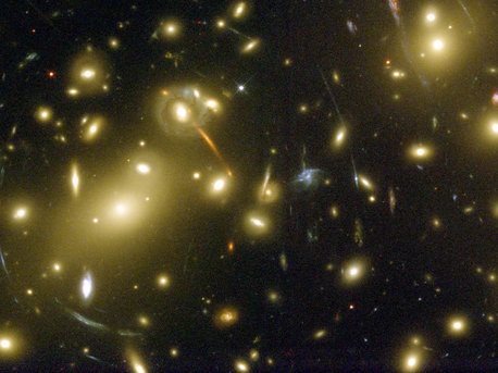 Gravitation kann Licht beugen, weshalb große Galaxienhaufen als Teleskope fungieren können. Fast alle hellen Objekte auf dieser Aufnahme des Hubble-Weltraumteleskops sind Galaxien des als Abell 2218 bekannten Haufens. Der Haufen ist so massereich und so kompakt, dass seine Gravitation das Licht der Galalaxien, die dahinter liegen, krümmt und fokussiert. Ein Ergebnis daraus ist, dass Mehrfachbilder dieser Hintergrundgalaxien zu langen, blassen Bögen verzerrt werden - ein einfacher Linseneffekt, den man mit dem Betrachten weit entfernter Straßenlampen durch ein Weinglas vergleichen kann.