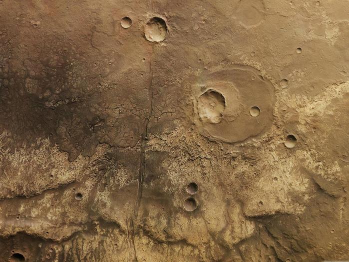 Diese senkrechte Farb-Draufsicht auf ein Gebiet südöstlich des Marscanyons Ma'adim Vallis im Marshochland wurde aus dem senkrecht blickenden Nadirkanal und den schräg auf die Oberfläche gerichteten Farbkanälen des Kamerasystems HRSC erstellt; Norden ist rechts im Bild.

Das Gebiet ist von ausgedehnten, erkalteten Lavaströmen gekennzeichnet. In der Farbdarstellung lässt sich gut ein etwa quer durch die Bildmitte verlaufender Übergang von dunklem Material im Westen der Region (obere Bildhälfte) zu hellerem Material im unteren Bildteil beobachten. Dabei handelt es sich um die vordere Fließfront eines Lavastroms aus Basalt.

In der unteren Bildhälfte sind östlich der Fließfronten der Lavadecken so genannte "Runzelrücken" zu erkennen, die über viele Kilometer eine Geländestufe zu den tiefer gelegenen Lavadecken ausbilden.

Im nördlichen Teil des Gebietes, rechts der Bildmitte, ist ein etwa 20 Kilometer großer Einschlagkrater zu erkennen. Dieser Krater wurde von Lava zu einem großen Teil verfüllt, ist also früher als der Lavastrom entstanden. Später bildete sich durch einen weiteren Einschlag ein kleinerer, etwa sieben Kilometer großer Krater im südlichen Teil des alten Kraters. Durch die Bildmitte verläuft in Ost-West-Richtung, also von unten nach oben, eine insgesamt über 200 Kilometer lange Störungszone. 