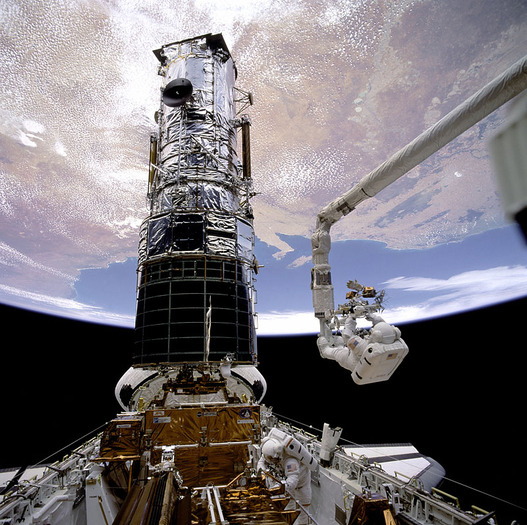 Der Astronaut Story Musgrave an der Spitze des Roboterarms bereitet sich auf die erste Service Mission des Hubble Weltraumteleskops vor