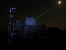 Goddard's Laser Ranging Facility directing a laser (green beam) toward the LRO spacecraft in orbit around the moon (white disk). The moon has been deliberately over-exposed to show the laser.