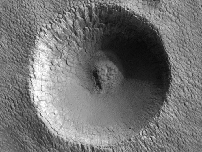 Ein Einschlagskrater am Südpol des Roten Planeten. Sein Durchmesser beträgt etwa 330 Meter. Wie man glaubt, sind die polaren Ablagerungen auf dem Mars sehr jung, weil es keine großen Krater und sehr wenige kleine Krater auf ihnen gibt.