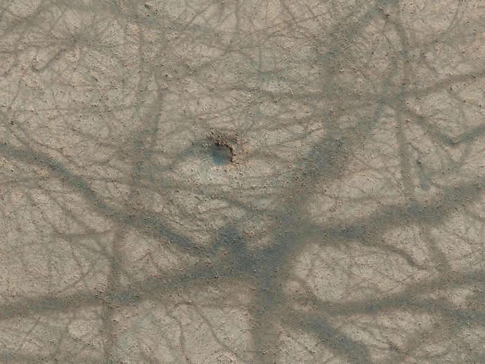 Ein winziger Einschlagskrater und ein Ineinandergreifen  verschiedener Staub-Teufel-Pfade auf der Marsoberfläche.
