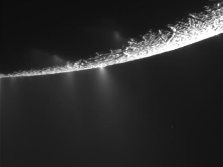 Südpolregion des Saturnmonds Enceladus beim letzten Vorbeiflug am 21. November 2009. Deutlich sichtbar:  Fontänen aus Eispartikeln schießen in den schwarzen Enceladus-Himmel. Der mengenmäßig eigentlich vorherrschende Wasserdampf bleibt unsichtbar.
