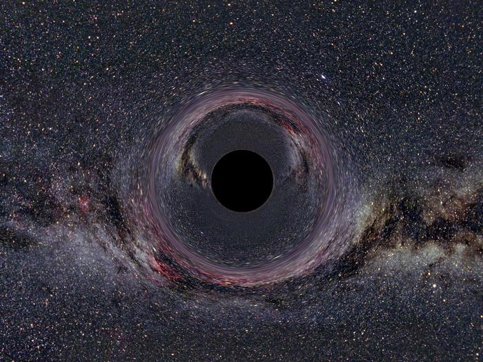 Das computersimulierte Bild zeigt ein fiktives Schwarzes Loch von 10 Sonnenmassen aus 600 Kilometer Abstand. Die Milchstraße im Hintergrund erscheint durch die Raumkrümmung verzerrt und doppelt.