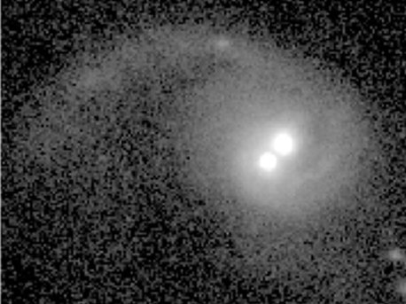 Eine Aufnahme der ACS-Kamera des Hubble Teleskops von der Galaxie COSMOS J100043.15+020637.2.  Der nach links durch Gezeitenkräfte verursachte Arm der Galaxie ist mit einer anderen galaxie kollidiert. Daher befinden sich jetzt zwei supermassereiche schwarze Löcher im Zentrum dieser Galaxie.  Ein Team von Astronomen hat nun bestätigt, dass die beiden hellen Punkte im Zentrum dieser Galaxie  mit den beiden Schwarzen Löchern der Ursprungsgalaxien assoziiert sind und sich auf das gravitative Zentrum der Galaxie zubewegen.