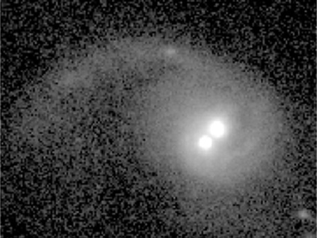 An image of the galaxy COSMOS J100043.15+020637.2 taken with the Advanced Camera for Surveys on the Hubble Space Telescope. The tidal tail of stars, gas, and dust shows that this galaxy recently merged with another galaxy, which brought two supermassive black holes into this galaxy. A team of astronomers confirmed that the two bright nuclei near the center of the galaxy correspond to the two black holes, which are waltzing under the effects of gravity towards the galaxy center.