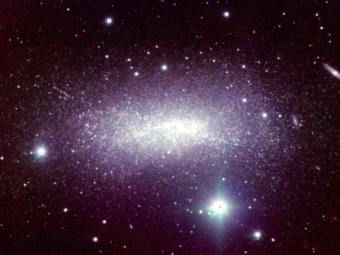 Shows the faint irregular dwarf galaxy NGC 1569, located 6.2 million light-years from Earth. This galaxy contains several large stellar clusters with episodic star formation at a rate of more than 100 times faster than we observe in our own galaxy. In visible light, the core of the galaxy shows only three large stellar clusters, each containing more than one million stars. With LUCIFER it became possible to peer through the cosmic dust and to reveal many more compact star forming regions.