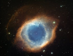 The blue-green glow in the center comes from oxygen atoms shining under effects of the intense ultraviolet radiation of the central star and the hot gas. Further out from the star and beyond the ring of knots, the red color from hydrogen and nitrogen domi